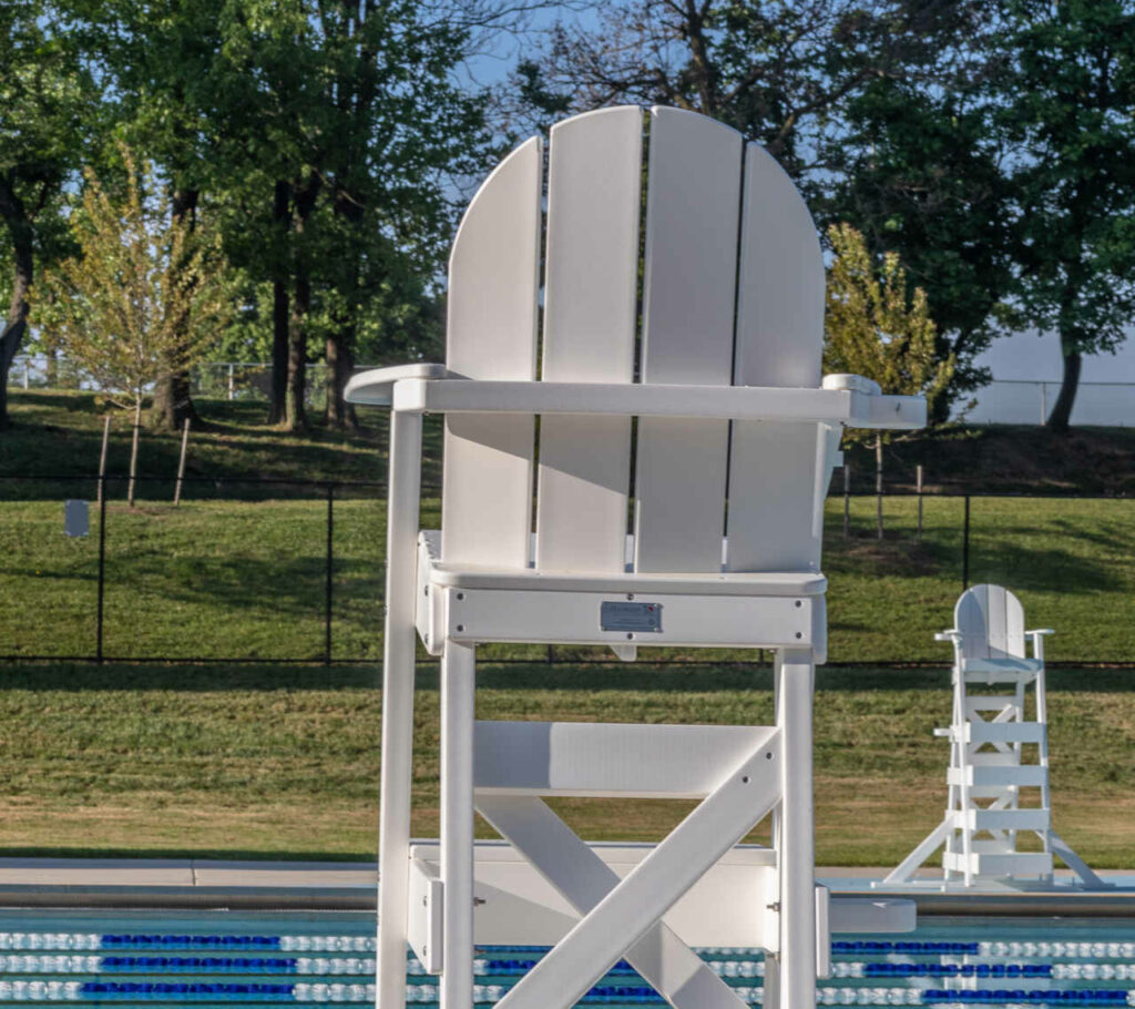 a white lifeguard chair next to a swimming pool.