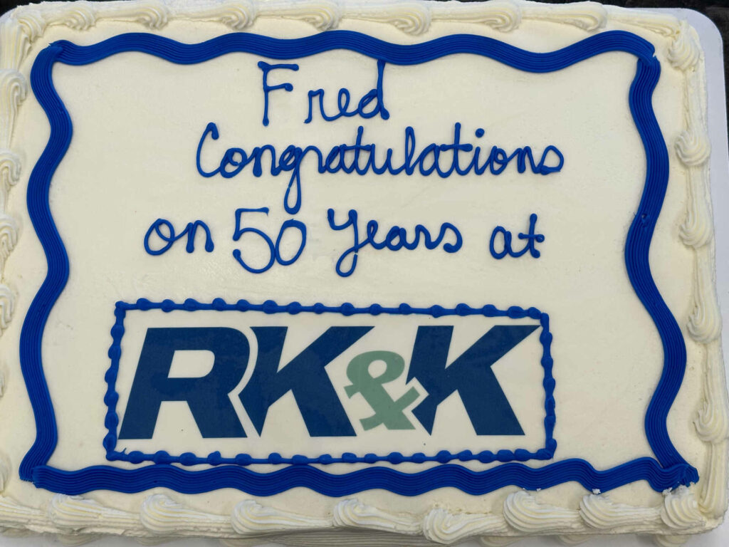 a white cake with blue lettering with the words "Fred congratulations on 50 years at RK&K"