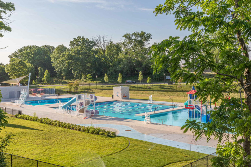 a swimming pool in a park with playground equipment.